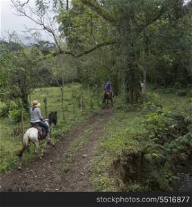 Female tourists enjoying horseback riding in forest, Finca El Cisne, Honduras
