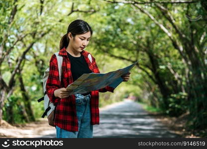 Female tourists stand and look at the map on the road.