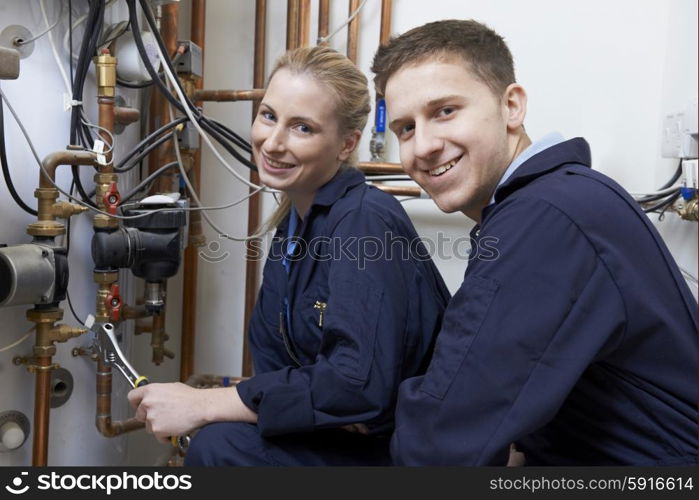 Female Trainee Plumber Working On Central Heating Boiler