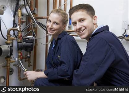Female Trainee Plumber Working On Central Heating Boiler