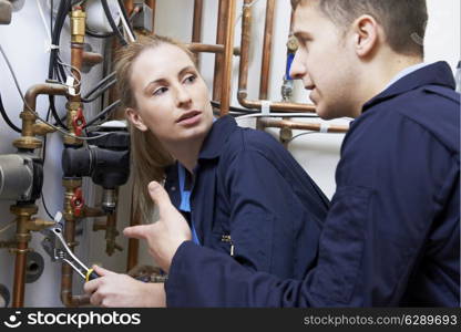 Female Trainee Plumber Working On Central Heating Boiler