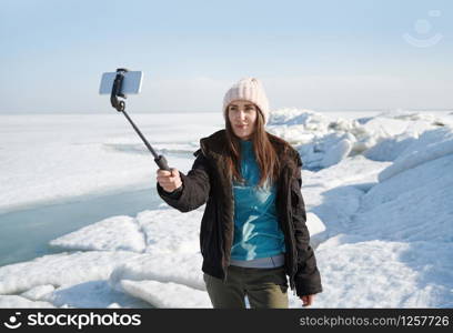 Female traveler at Jokulsarlon Glacial Lagoon using monopod to make selfie picture