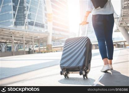 Female traveler tourist walking with luggage at terminal station. Activity and lifestyle concept. Business people and long holiday vacation theme. Back view