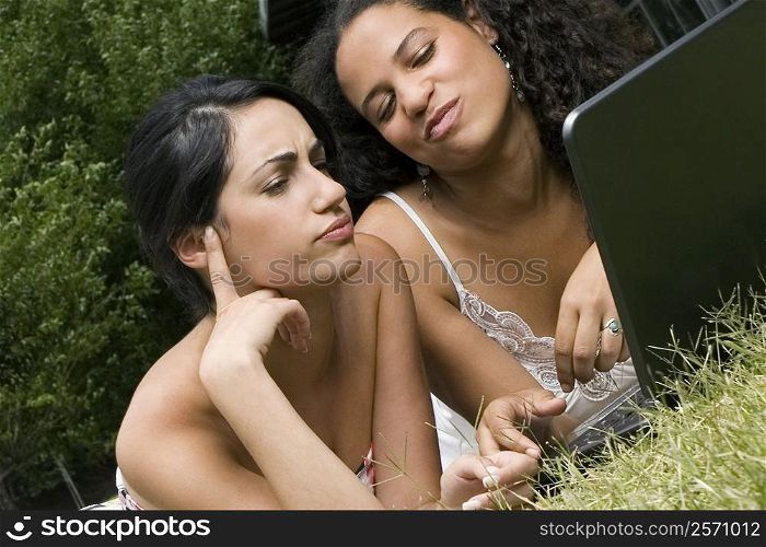 Female university students working on a laptop in a lawn