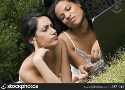 Female university students working on a laptop in a lawn