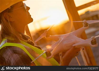 Female Unmanned Aircraft System (UAS) Quadcopter Drone Pilot Holding Drone at Construction Site.