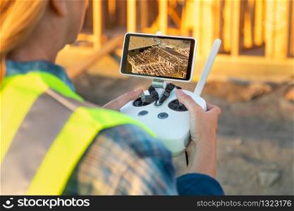 Female Unmanned Aircraft System (UAV) Quadcopter Drone Pilot with Controller Inspecting New House Framing.