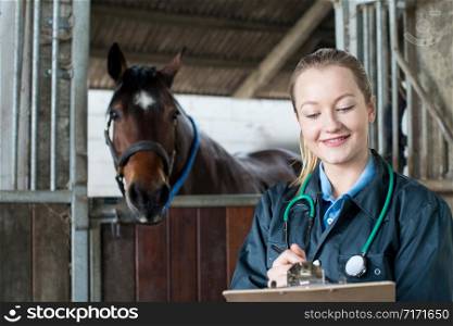 Female Vet Examining Horse In Stable