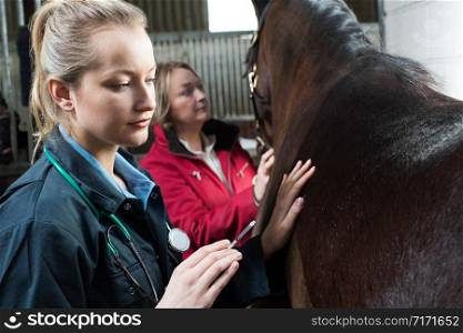 Female Vet Giving Injection To Horse In Stable