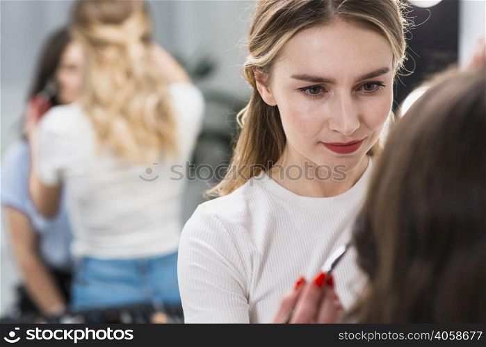 female visagiste putting makeup client