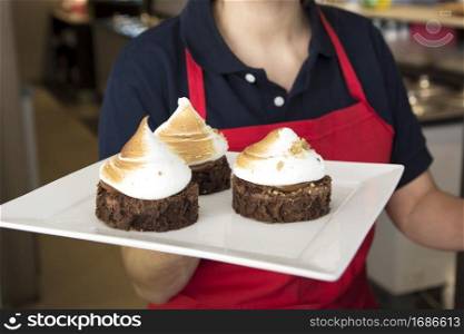 female waitress holding chocolate cake with whipped cream tray
