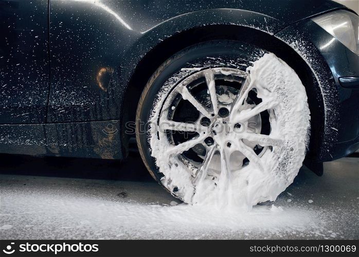 Female washer applies foam to the wheel, car wash. Woman cleans vehicle, carwash station, car-wash business. Female washer applies foam to the wheel, car wash