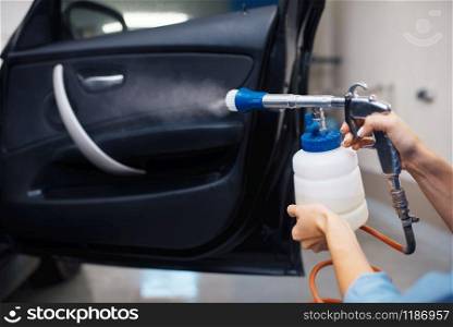 Female washer cleans automobile interior, car wash. Woman washes vehicle, carwash station, car wash business. Female washer cleans automobile interior, car wash