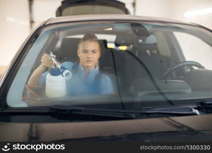 Female washer cleans automobile interior, view through the windshield, car wash. Woman washes vehicle, carwash station, car-wash business