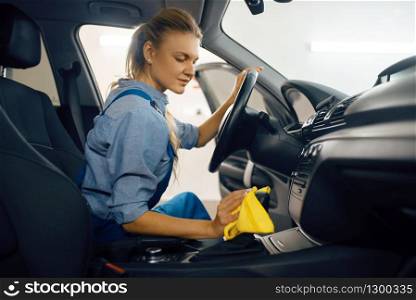 Female washer with sponge cleans automobile door trim, car wash service. Woman washes vehicle, carwash station, car-wash business. Female washer cleans automobile door trim