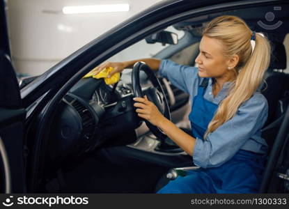 Female washer with sponge cleans automobile interior, car wash service. Woman washes vehicle, carwash station, car-wash business. Female washer with sponge cleans car interior