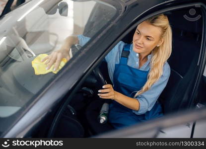 Female washer with sponge cleans automobile interior, car wash service. Woman washes vehicle, carwash station, car-wash business