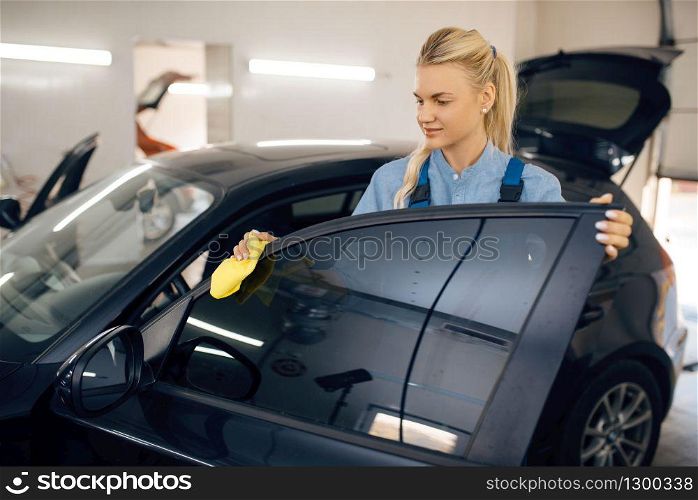 Female washer with sponge cleans automobile interior, car wash service. Woman washes vehicle, carwash station, car wash business. Female washer with sponge cleans car interior