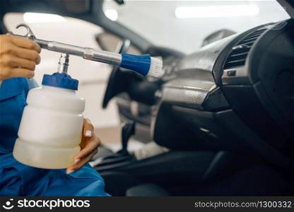 Female washer with steam cleaner cleans automobile interior, car wash service. Woman washes vehicle, carwash station, car-wash business