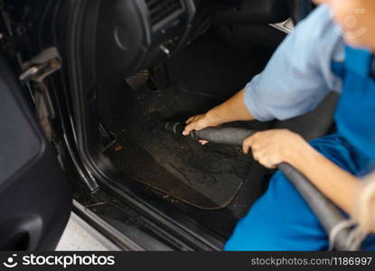 Female washer with vacuum cleaner cleans auto interior, car wash service. Woman washes vehicle, carwash station, car-wash business. Woman with vacuum cleaner, car wash service