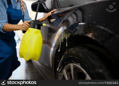 Female washer with wax spray cleans automobile, waxing on car wash service. Woman washes vehicle, carwash station, car-wash business