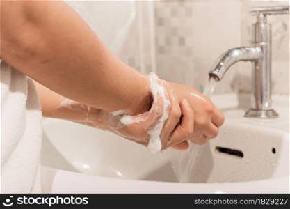 Female washes his hands with soap over a sink in the bathroom. Concept of hygiene treatment.