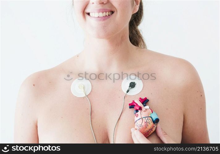 female with electrocardiogram leads hand with figurine heart