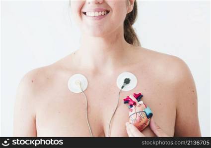 female with electrocardiogram leads hand with figurine heart