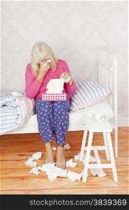 Female with pink pajama and tissues sitting on bed in desperation