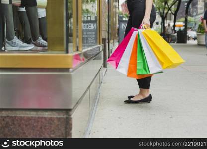 female with shopping bags near shop window
