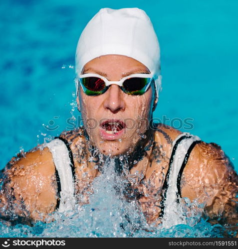 Female with tattoos swimming breaststroke on training