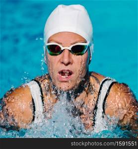 Female with tattoos swimming breaststroke on training