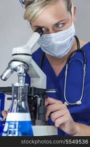 Female woman medical scientist or doctor in laboratory using a microscope wearing face or surgical mask