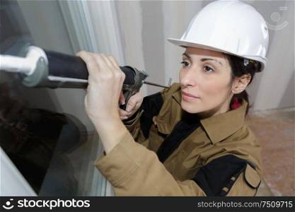 female worker doing a silicone joint on a window