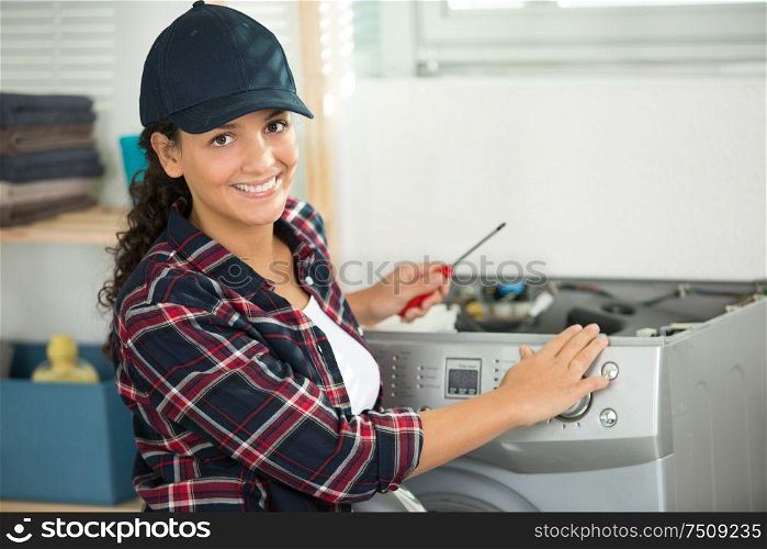 female worker holding a screwdriver next to a washing machine