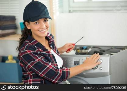 female worker holding a screwdriver next to a washing machine