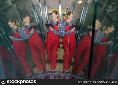 female worker holding tablet seen in reflected mirror images