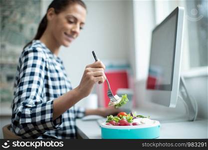 Female Worker In Office Having Healthy Chicken Salad Lunch At Desk