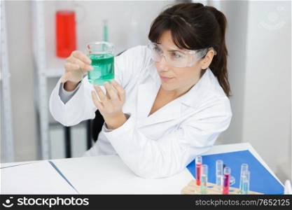 female worker mixing blue liquid in a beaker