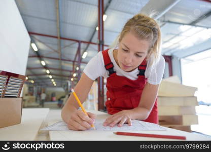 female worker on apron drawing blueprint