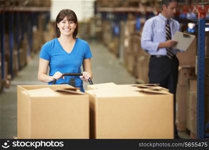 Female Worker Pulling Pallet In Warehouse