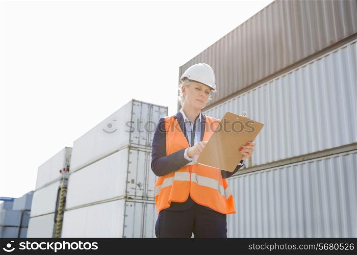 Female worker reading clipboard in shipping yard