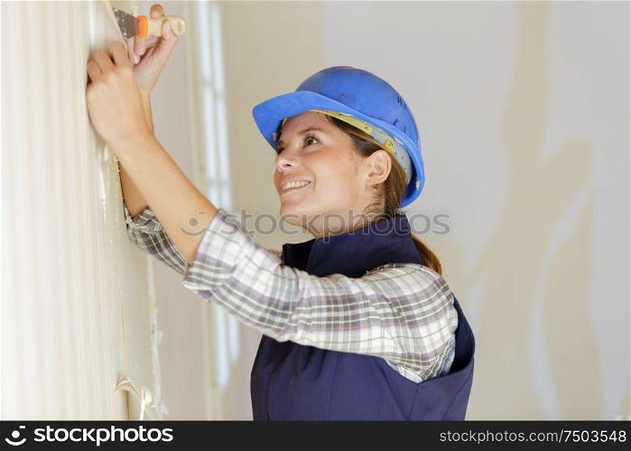 female worker sand papering the wall