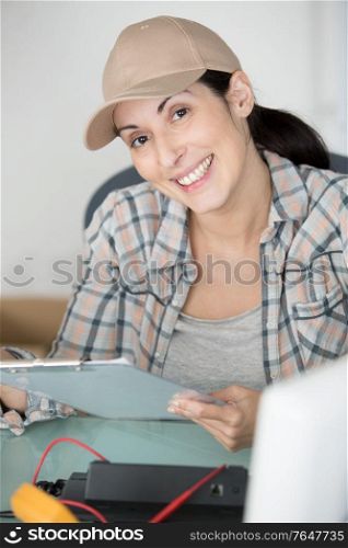 female worker sat at desk holding a clipboard