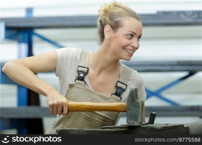 female worker using hammer over anvil