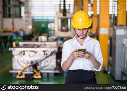 female worker with helmet check production hardware stock in factory warehouse by company application in smartphone. Manufacturing industry and technology. Industry with inventory concept.