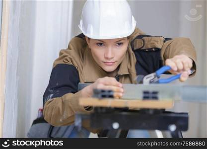 female worker with helmet holding pliers