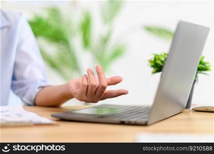 Female worker working with laptop and pointing at screen