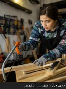 female workshop cutting wood plank