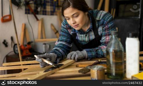 female workshop painting wood plank